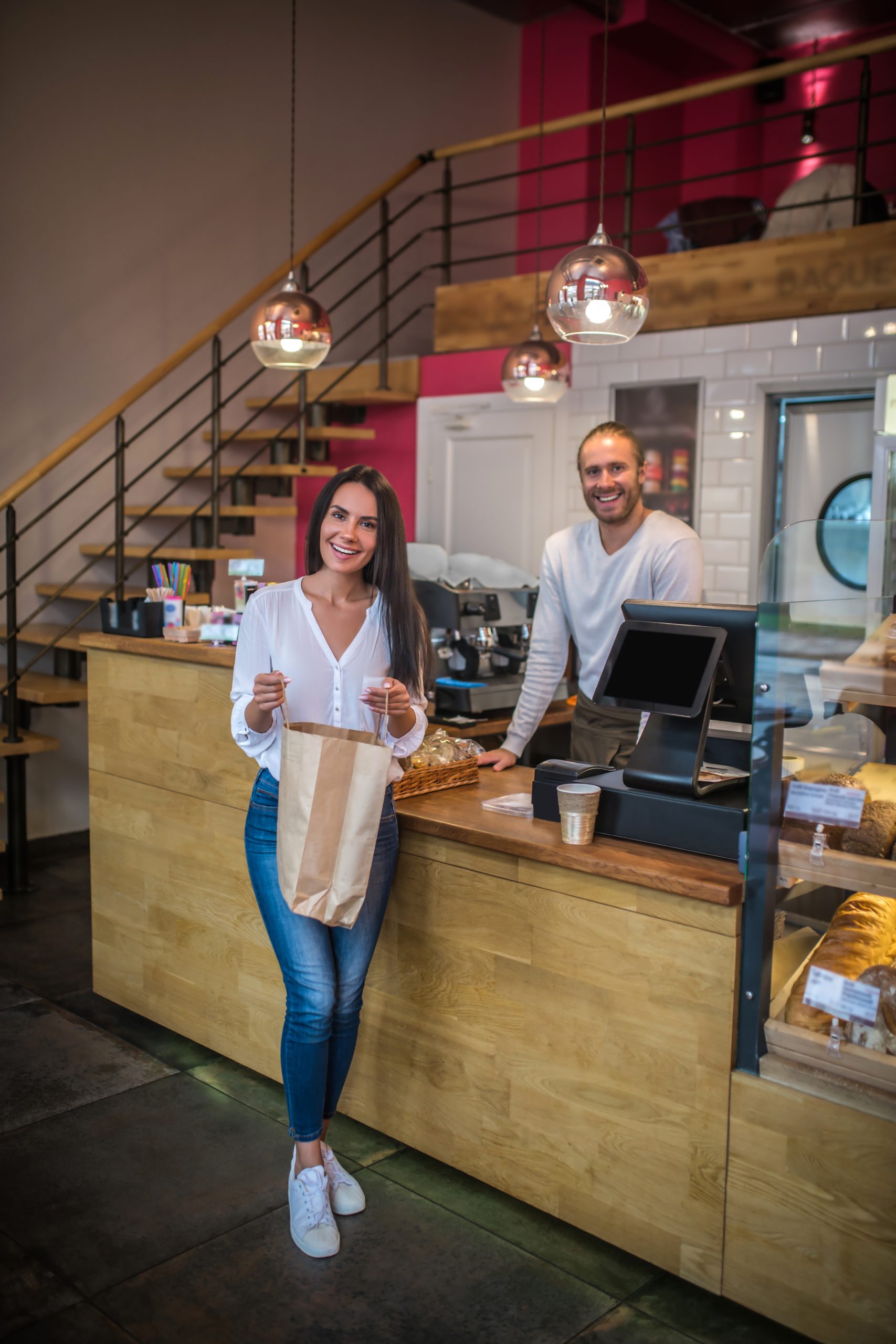Happy after buying. Woman wearing jeans and white blouse feeling happy after buying pastry